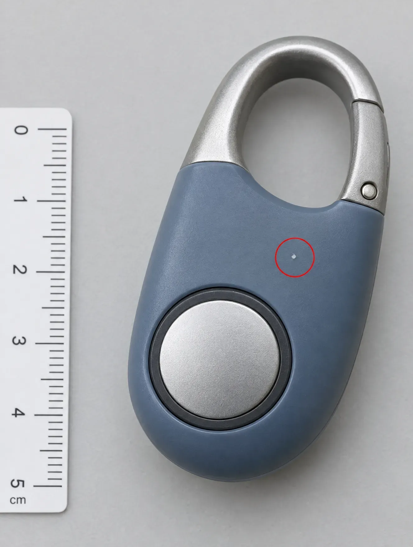 A small white mark on a blue plastic product, circled in red beside a ruler