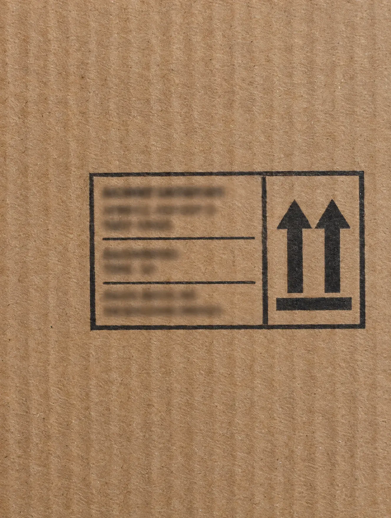 Close-up of a printed shipping mark and 'this way up' symbol on a kraft export carton