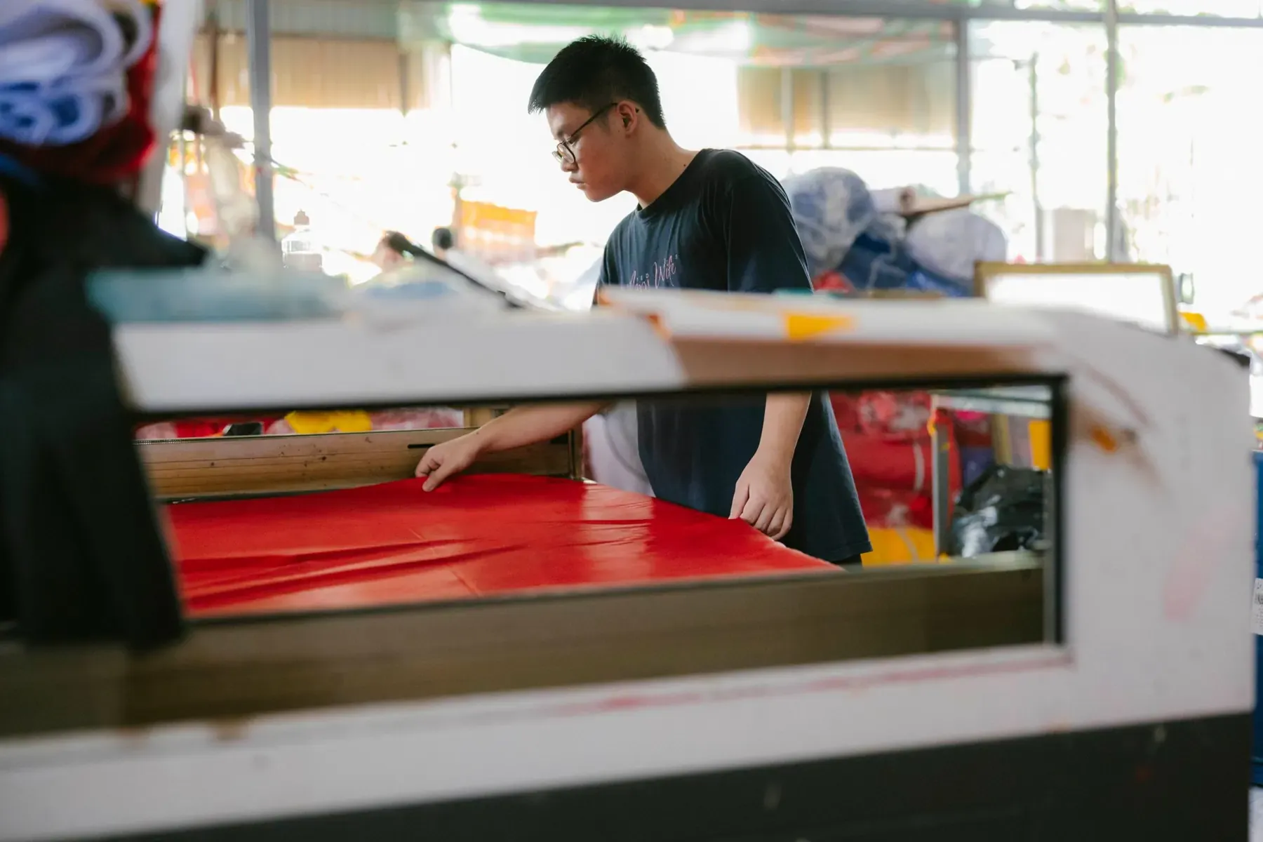 A worker checking fabric at a cutting table in a textile workshop